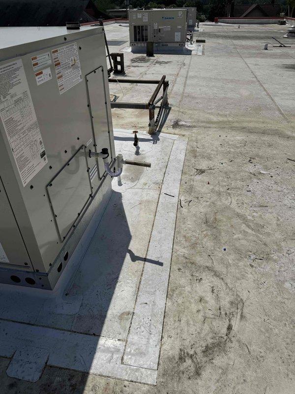 Completed commercial rooftop installation of three Daikin RTU units on flat membrane roof with proper equipment mounting and support structures. Installed concrete equipment pads, metal support frames, and electrical control panels with all necessary connections and technical specifications verified. All units positioned and secured according to manufacturer specifications with adequate clearances for service access and proper drainage considerations on existing roof surface.