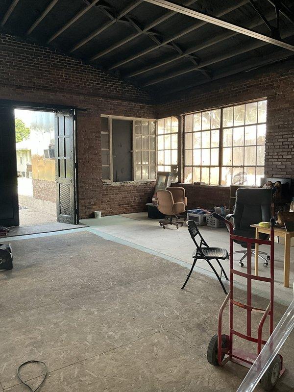 Conducted site assessment for complete HVAC system installation at commercial location undergoing full renovation with no existing equipment. Evaluated large open warehouse-style space with exposed ceiling joists, new interior wall framing, and concrete flooring to determine equipment sizing, placement, and ductwork routing requirements. Documented space layout including exposed brick walls, industrial windows, and ceiling structure to plan overhead venting installation through exposed beam system as requested.