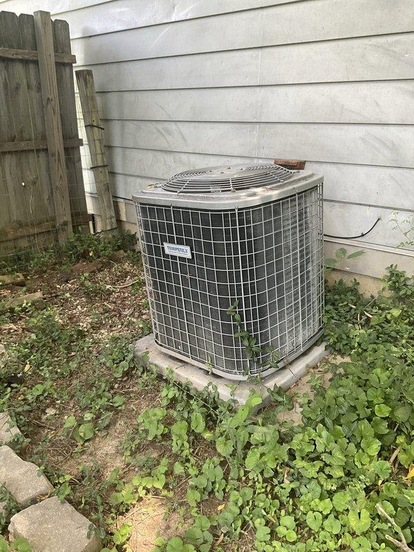 Conducted comprehensive assessment of non-functional residential HVAC system including outdoor condenser unit and aging Tempstar furnace located in interior utility closet. Documented existing equipment condition with detailed photography showing weathered outdoor unit on concrete pad and furnace installation alongside water heater, noting significant wear and system failure requiring complete replacement estimate for both heating and cooling components.