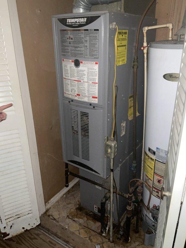 Conducted comprehensive assessment of non-functional residential HVAC system including outdoor condenser unit and aging Tempstar furnace located in interior utility closet. Documented existing equipment condition with detailed photography showing weathered outdoor unit on concrete pad and furnace installation alongside water heater, noting significant wear and system failure requiring complete replacement estimate for both heating and cooling components.
