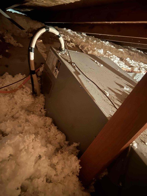 Responded to ceiling leak complaint suspected to be related to AC system. Accessed attic space and inspected HVAC ductwork and condensate drainage system. Found visible moisture condensation and discoloration on metal plenum box with water staining on surrounding surfaces. Inspected PVC condensate drain line with elbow joint near ductwork and confirmed proper drainage pathway. Documented conditions of post-flood AC unit showing signs of age and moisture exposure on metal components. Verified heating and cooling system remains operational at time of inspection.