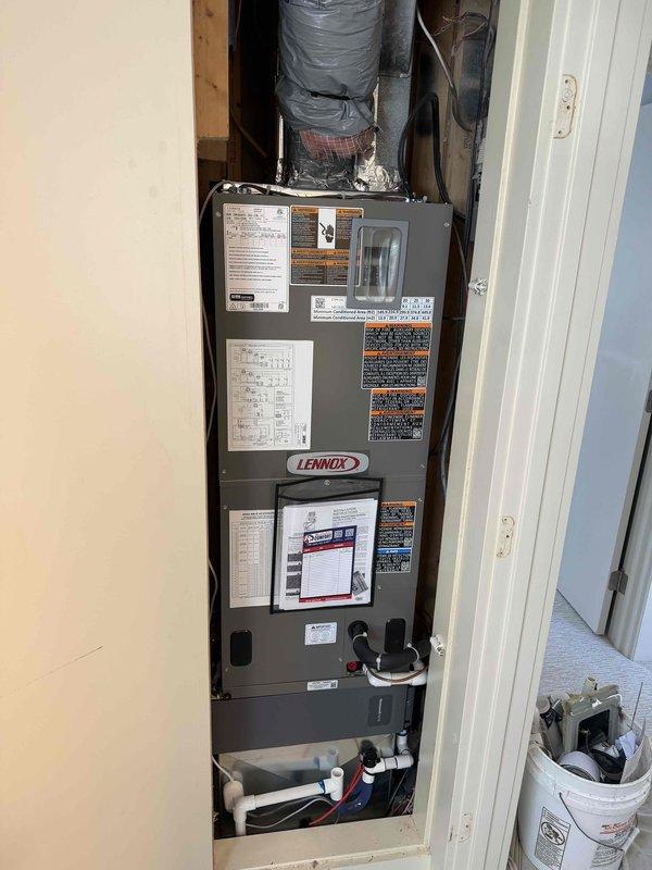 Completed full installation of Lennox heat pump system for upstairs zone. Installed new Lennox air handler unit in interior utility closet with proper vertical mounting and secure positioning. Connected insulated ductwork with metallic flexible insulation extending to distribution system. Established proper condensate drainage with drain pan installation. Completed all electrical connections and control wiring per manufacturer specifications.

Installed outdoor heat pump condenser unit on concrete pad against exterior wall with gray-blue siding. Positioned unit alongside existing HVAC equipment with adequate clearance for service access and airflow. Ran refrigerant line set from outdoor unit to indoor air handler, including insulated copper piping with proper routing along exterior wall. Secured all refrigerant connections and performed leak testing. Applied decorative rock ground cover around equipment pad for drainage and aesthetics.

System tested and verified operational with prope