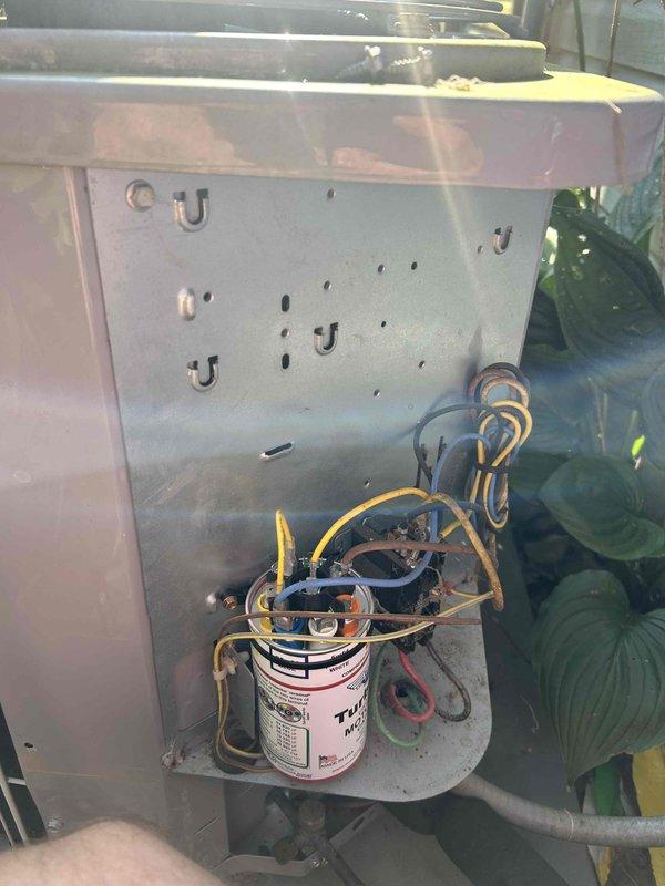Responded to no cooling complaint on residential air conditioning unit. Upon inspection, found failed dual run capacitor with visible deterioration and compromised electrical connections. Replaced defective capacitor with new Turbo brand unit, cleaned debris and cobwebs from electrical compartment, secured all wire connections, and verified proper operation of contactor and compressor circuit. System tested and confirmed cooling operation restored with normal amperage readings.