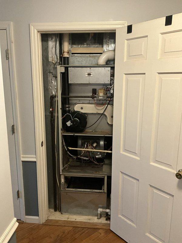 Conducted comprehensive assessment of existing HVAC system for complete replacement estimate. Evaluated aging air handler unit located in interior utility closet, noting significant dust accumulation, deteriorated surfaces, and overall equipment condition indicating end of service life. Documented existing vertical installation configuration with metal ductwork, refrigerant lines with partial insulation degradation, and confined access space within closet area. Inspected exterior mechanical components and noted evidence of moisture exposure and weathering on building foundation and surrounding areas. Provided detailed replacement system recommendations and equipment options suitable for the existing installation footprint and configuration.