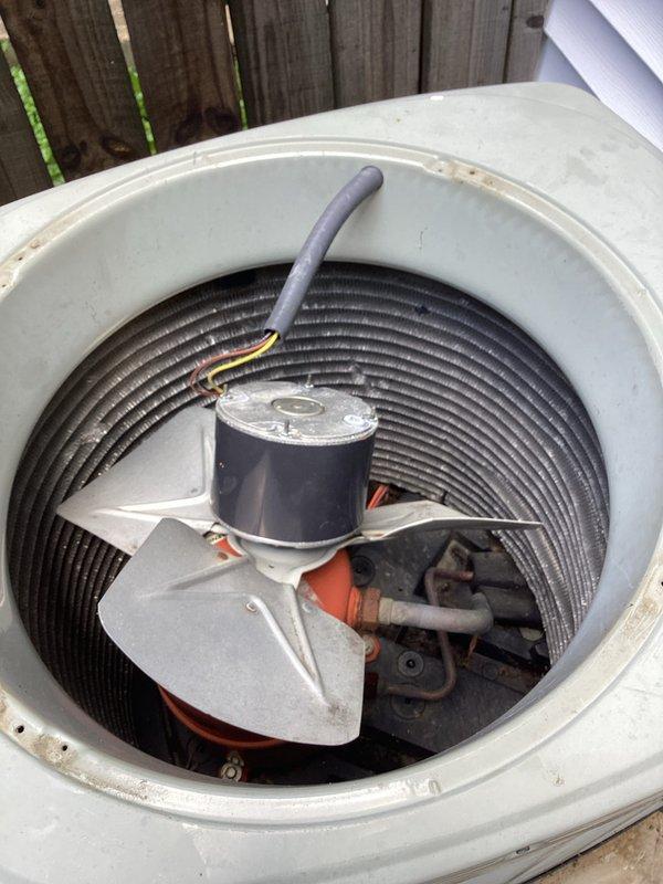 Responded to no-cooling call on outdoor condensing unit. Upon arrival, found condenser fan motor improperly mounted and free-floating inside unit housing after recent motor replacement by homeowner. Motor assembly not secured correctly to top panel mounting brackets, creating potential for damage to electrical connections and internal components. Inspected new capacitor installation and verified proper electrical connections to compressor and fan motor terminals. Documented improper motor mounting configuration with photos showing cross-shaped support bracket system and loose motor housing. Advised that motor must be properly secured to manufacturer specifications before unit operation to prevent equipment damage and ensure safe functionality.