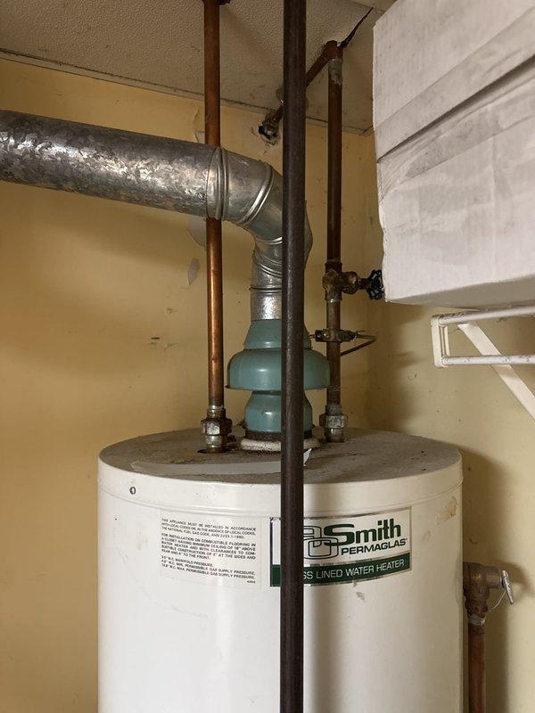 Responded to service call regarding A.O. Smith Permaglas electric tanked water heater with improper venting configuration identified by gas utility company during meter replacement. Upon inspection, confirmed water heater unit operational but venting ductwork improperly installed with flexible metallic duct incorrectly routed from top of unit. Documented existing conditions showing inadequate venting system that prevented utility from restoring gas service to property.