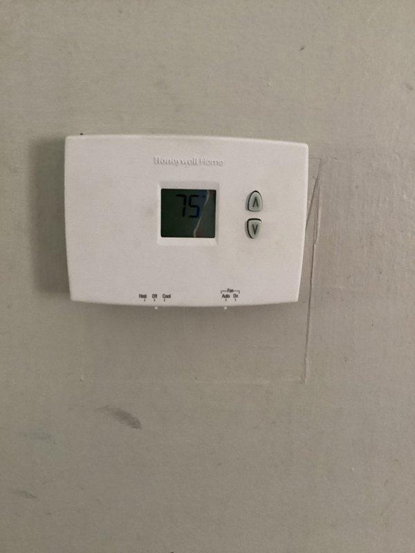 Responded to no cooling complaint on commercial HVAC unit. Upon arrival, inspected condenser fan assembly and found motor had failed, preventing proper heat rejection from the system. Verified thermostat was calling for cooling at 75 degrees but unit was unable to satisfy demand due to inoperative condenser fan. Documented equipment condition with photos showing fan guard assembly and thermostat display for service records.