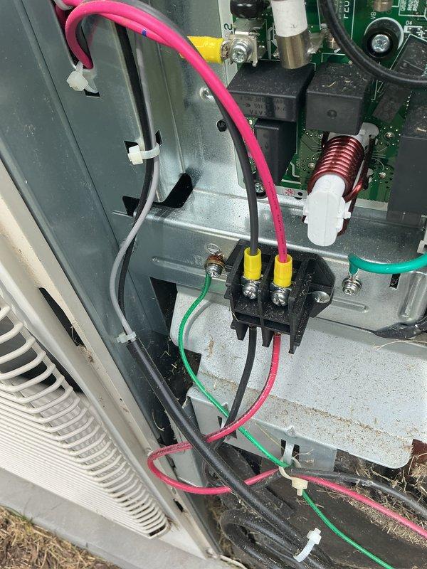 # HVAC Maintenance - Cooling System Service

Completed basic monthly cooling maintenance visit on residential air conditioning system. Upon arrival, performed comprehensive inspection of outdoor condenser unit and electrical components. Noted significant accumulation of dirt, debris, pollen, and organic matter on condenser coil and filter surfaces, restricting airflow and reducing system efficiency.

Inspected electrical connections at terminal block, verifying proper wire terminations on all power and control circuits including line voltage connections. Confirmed secure connections on brass terminal screws with pink, yellow, green, and black wiring properly seated. Examined control board circuitry showing normal condition with all capacitors, inductors, and electronic components functioning within specifications. All wire management clips and routing appeared secure with no signs of chafing or damage.

Evaluated protective white metal grid cage surrounding condenser unit, confirming s
