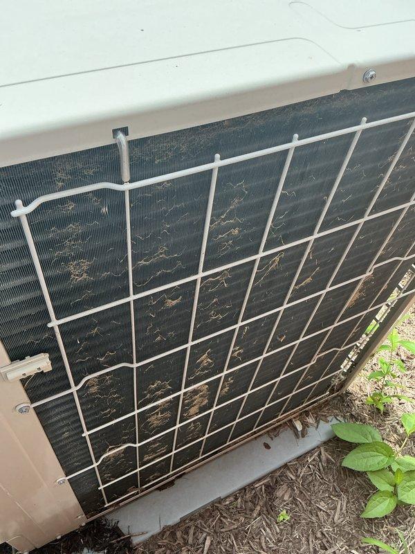 # HVAC Maintenance - Cooling System Service

Completed basic monthly cooling maintenance visit on residential air conditioning system. Upon arrival, performed comprehensive inspection of outdoor condenser unit and electrical components. Noted significant accumulation of dirt, debris, pollen, and organic matter on condenser coil and filter surfaces, restricting airflow and reducing system efficiency.

Inspected electrical connections at terminal block, verifying proper wire terminations on all power and control circuits including line voltage connections. Confirmed secure connections on brass terminal screws with pink, yellow, green, and black wiring properly seated. Examined control board circuitry showing normal condition with all capacitors, inductors, and electronic components functioning within specifications. All wire management clips and routing appeared secure with no signs of chafing or damage.

Evaluated protective white metal grid cage surrounding condenser unit, confirming s