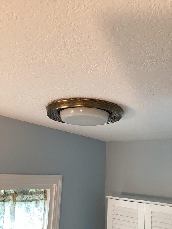Replaced two original bathroom exhaust fans with new ceiling-mounted fixtures featuring decorative bronze trim and white dome covers. Inspected toilet flushing mechanism to diagnose extended flush cycle issue.