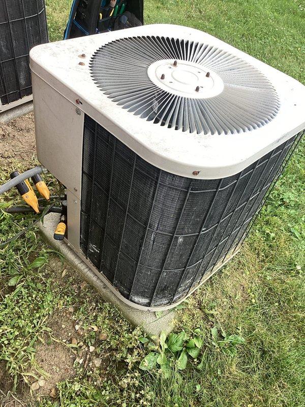 Responded to service call for heat pump not keeping up with heating demand. Upon arrival, performed visual inspection of outdoor unit which showed signs of weathering and dirt accumulation on exterior surfaces and protective grilles. Condenser unit appeared operational but exterior maintenance was needed. Documented equipment condition with photos showing copper refrigerant lines, electrical conduit routing, and overall installation setup. Unit positioned on concrete pad against brick wall in residential setting with adequate clearance for airflow.