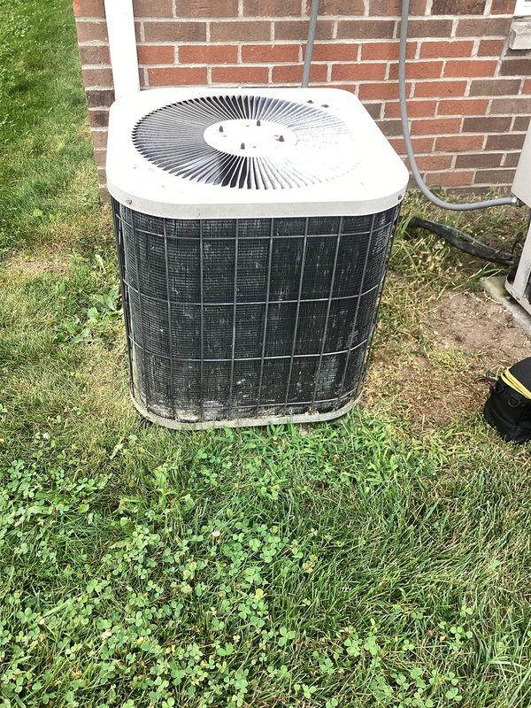 Responded to service call for heat pump not keeping up with heating demand. Upon arrival, performed visual inspection of outdoor unit which showed signs of weathering and dirt accumulation on exterior surfaces and protective grilles. Condenser unit appeared operational but exterior maintenance was needed. Documented equipment condition with photos showing copper refrigerant lines, electrical conduit routing, and overall installation setup. Unit positioned on concrete pad against brick wall in residential setting with adequate clearance for airflow.