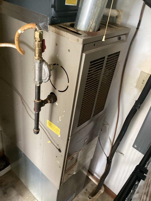 Responded to service call for air conditioning system not cooling properly. Upon inspection, found residential HVAC system with furnace and associated mechanical components in basement utility area. Performed diagnostic evaluation of cooling system including visual inspection of equipment, ductwork connections, and mechanical room installation. Documented existing equipment configuration showing furnace unit, water heater, copper piping assemblies, and valve components. Assessed valve assembly and plumbing connections on mounting panel for proper operation. Verified all visible components including pressure relief valves, electrical connections, and duct transitions. System photographed for service records showing current installation condition and equipment layout.
