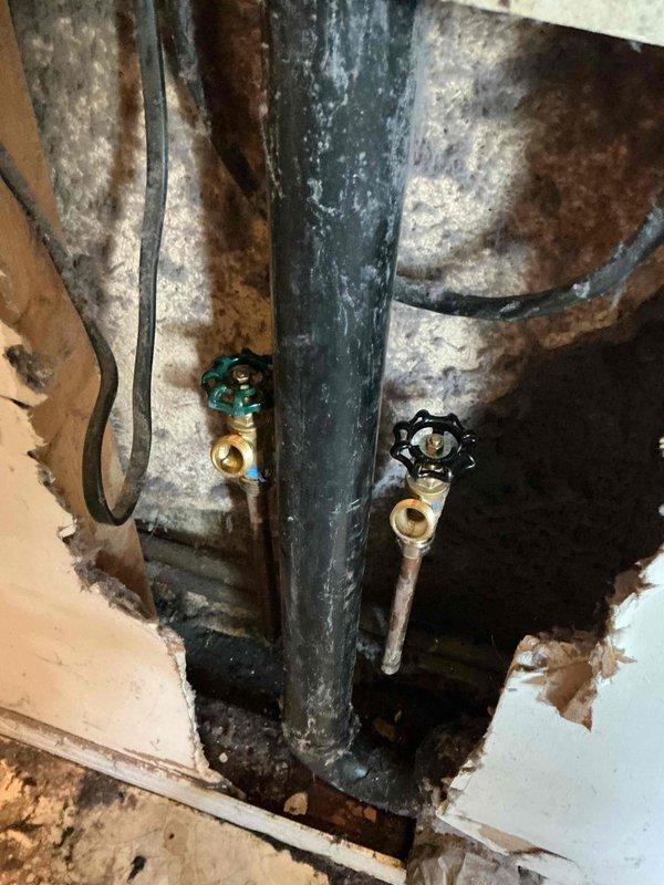 Responded to service call for malfunctioning washing machine supply valves that would not shut off completely. Upon arrival, accessed plumbing behind washer location and found two brass shut-off valves with deteriorated internal components preventing proper closure. Replaced both hot and cold water supply valves with new quarter-turn ball valves featuring color-coded handles for easy identification. Addressed significant water damage evident in wall cavity surrounding the plumbing, including stained insulation and drywall deterioration from previous valve leakage. Tested new valves for proper operation and complete shut-off capability to allow safe installation of new washing machine. Documented existing conditions with photos showing extent of water damage and successful valve replacement.