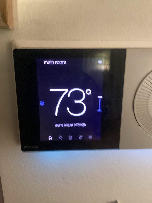 Responded to service call for air conditioning system failing to maintain setpoint temperature. Upon arrival, found Daikin thermostat displaying 73-74°F while set to 54°F, indicating significant temperature differential and inability to reach desired cooling setpoint. Inspected thermostat operation and verified display functionality showing "main room" zone with adjusted settings active. System evaluated for proper communication between thermostat and cooling equipment to address temperature control issue.