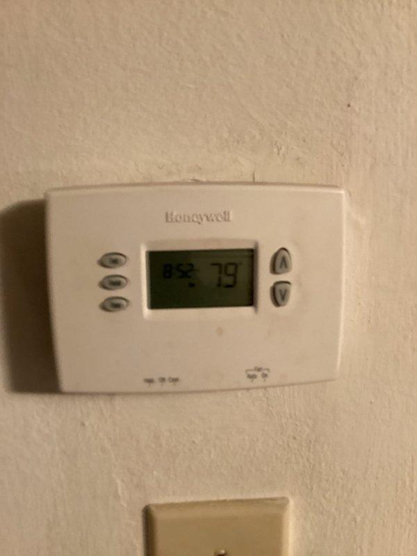# HVAC Service Call - No Cooling Condition

Responded to service call for no cooling on 10+ year old Tempstar residential air conditioning system. Upon arrival, found thermostat displaying 79°F with no cooling occurring. Performed visual inspection of outdoor condenser unit, which showed significant age-related wear, dirt accumulation, and vegetation growth around base affecting airflow. Unit exhibited weathering consistent with extended outdoor exposure and lack of regular maintenance.

Conducted diagnostic evaluation of system components including electrical connections at exterior junction box, compressor operation, and refrigerant levels. Assessed condenser coil condition through protective wire mesh cage, noting debris buildup restricting heat transfer efficiency. Evaluated fan motor operation and blade condition at top grille assembly.

Cleared vegetation and debris from around condenser unit perimeter to restore proper airflow clearance. Inspected Honeywell digital thermostat fo