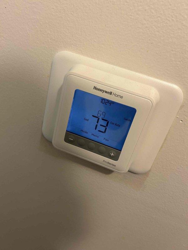 Responded to no cooling complaint on residential air conditioning system. Performed diagnostic evaluation of outdoor condensing unit and indoor thermostat operation. Verified thermostat settings showing 73°F setpoint with fan in auto mode, inspected outdoor unit installation including refrigerant line connections and electrical conduit, and assessed overall system condition to determine cause of inadequate cooling performance.