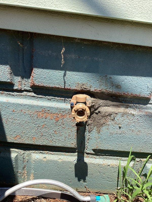 Responded to service callback for malfunctioning exterior hose bib that would not turn. Upon arrival, found severely corroded brass valve assembly mounted on exterior wall with significant rust staining and deterioration around pipe penetration point. Valve mechanism was seized due to age and weather exposure, preventing operation. Replaced failed hose bib with new frost-proof sillcock assembly, ensuring proper mounting and seal at wall penetration to prevent future water intrusion and rust damage. Tested new fixture for proper operation and verified no leaks at connection points.