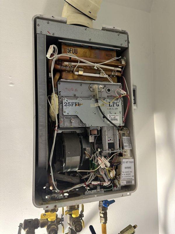 Completed installation of customer-provided tankless water heater unit with LPG gas connection. Mounted unit to wall, connected water supply lines with isolation valves featuring shutoff controls, installed flexible yellow corrugated gas line with proper fittings and pressure gauge, and verified all electrical wiring connections within the unit. Tested system operation including heat exchanger, blower motor assembly, ignition controls, and safety mechanisms to ensure proper functionality. All plumbing connections secured with brass fittings and isolation valves for maintenance access, ventilation ductwork properly connected, and unit confirmed operational.