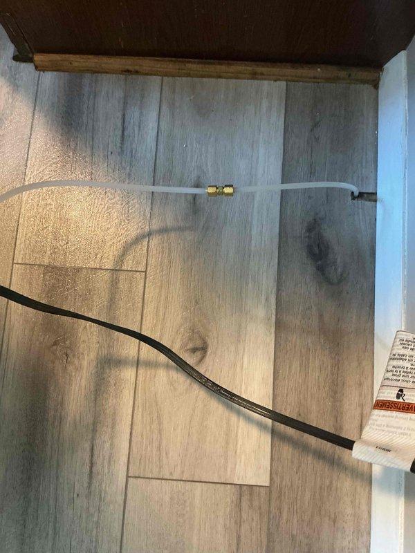 Responded to emergency water leak from refrigerator ice maker supply line. Upon arrival, identified compromised plastic water line with puncture causing active spray onto laminate flooring. Shut off water supply, removed damaged section of tubing, and installed new ice maker supply line with brass compression fittings to ensure leak-free connection. Verified system integrity and restored water supply with no leaks detected.