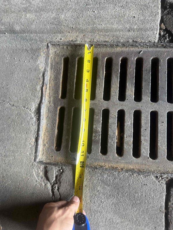 Responded to emergency safety hazard involving large ground openings creating dangerous conditions for excavation equipment and personnel. Inspected and documented existing drainage grate installations using measurement tools to assess dimensions and structural integrity of metal grates set into concrete surfaces. Photographed grate conditions showing weathering, debris accumulation, and proper drainage slot configurations for maintenance records and future repair planning.