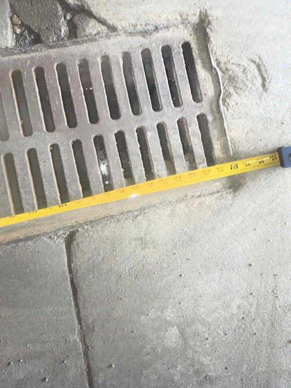 Responded to emergency safety hazard involving large ground openings creating dangerous conditions for excavation equipment and personnel. Inspected and documented existing drainage grate installations using measurement tools to assess dimensions and structural integrity of metal grates set into concrete surfaces. Photographed grate conditions showing weathering, debris accumulation, and proper drainage slot configurations for maintenance records and future repair planning.