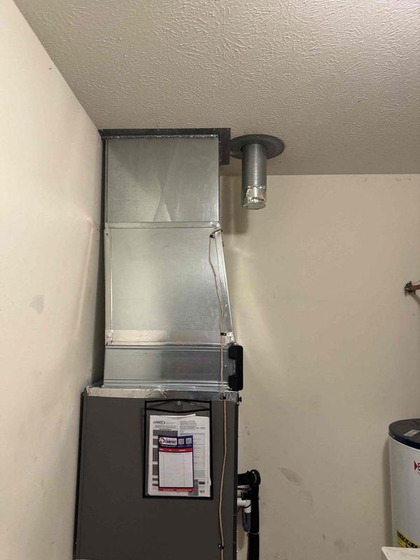 Completed full commercial HVAC system installation in interior utility room, including vertical air handler unit with associated ductwork and refrigerant lines. Rerouted electrical wiring to accommodate new equipment configuration and ensure proper power supply to system components. System installed in corner configuration with supply ductwork extending through ceiling, all connections secured and tested for proper operation.