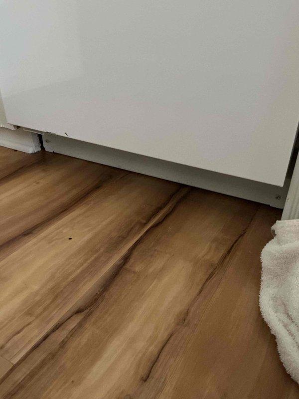 Responded to kitchen water leak investigation. Upon arrival, identified moisture damage on flooring near baseboard in corner area. Inspected potential sources including dishwasher and refrigerator water supply lines. Cleared items from affected area to access plumbing connections behind cabinetry. Examined supply lines, shut-off valves, and compression fittings for signs of active leaking or water intrusion. Customer advised to monitor area and provided recommendations for next steps pending source identification.