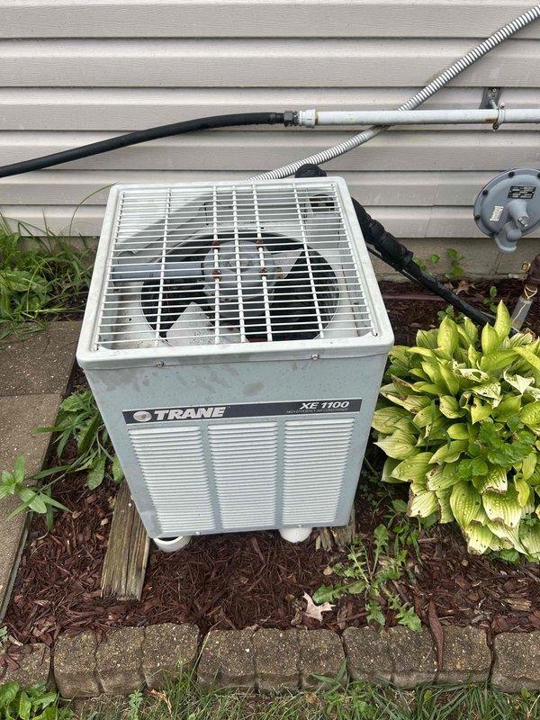Responded to no cooling call on Trane XE 1100 split system where outdoor condenser unit was not running while indoor air handler fan operated normally. Inspected outdoor unit electrical components including capacitor and wiring connections, documented system condition with photographs showing aged components with accumulated dirt and general wear. Diagnosed failure, performed necessary repairs to restore outdoor unit operation and system cooling capacity.