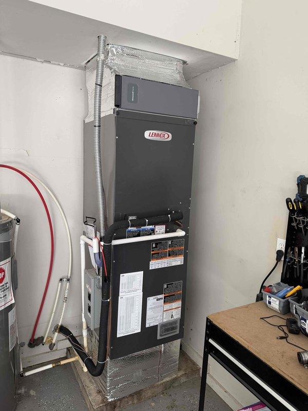 Completed full installation of Lennox heat pump system including indoor air handler unit and all associated ductwork connections. Air handler was mounted on protective base platform in utility area with flexible insulated ductwork properly connected and sealed. System commissioning performed with temperature verification showing 87.2°F supply air temperature, confirming proper heat pump operation. All equipment labeled appropriately with technical specifications and safety warnings per manufacturer requirements.