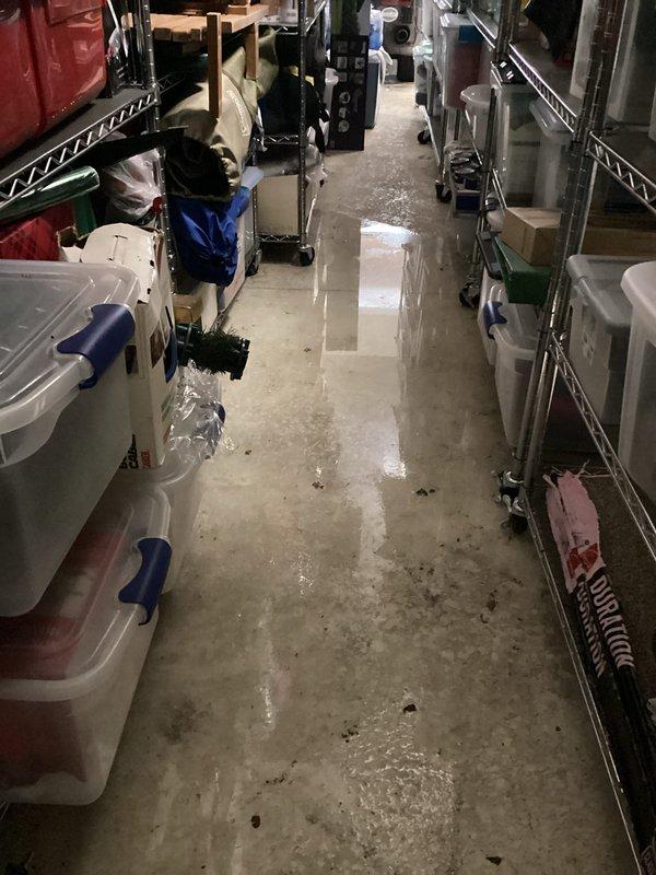 Responded to water leak call originating from HVAC unit located in garage area. Upon arrival, customer was not present as previously communicated. Conducted thorough inspection of the affected area, which included basement storage space with extensive water accumulation on concrete flooring. Documented moisture damage with photographic evidence showing standing water, wet patches, and reflective puddles throughout the corridor and storage areas. Identified water staining patterns on concrete surface indicating active leak from overhead unit. Inspected wire shelving units, stored items, and dehumidifier equipment in vicinity of leak source to assess extent of water intrusion and potential secondary damage to customer property.