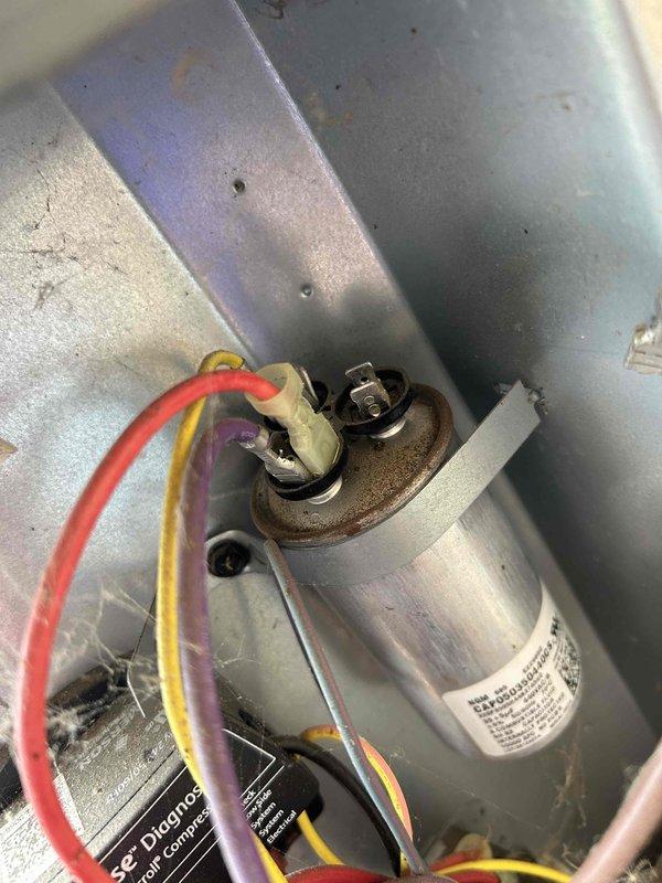 Responded to no cooling complaint on 10+ year old outdoor condensing unit. Performed diagnostic testing of electrical components using digital multimeter, with focus on capacitor and compressor circuit. Inspected internal wiring connections, terminal posts, and ComSense module within electrical compartment, noting accumulated dust and debris consistent with age of equipment.