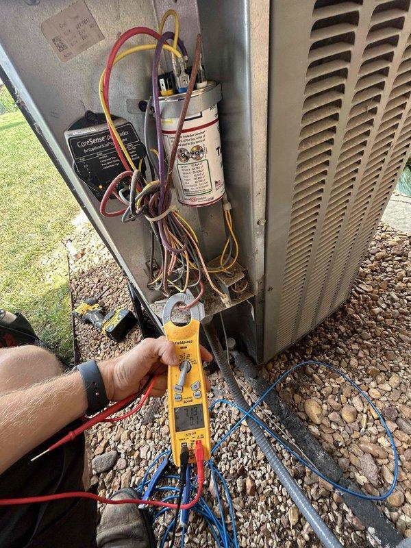 Responded to no cooling complaint on 10+ year old outdoor condensing unit. Performed diagnostic testing of electrical components using digital multimeter, with focus on capacitor and compressor circuit. Inspected internal wiring connections, terminal posts, and ComSense module within electrical compartment, noting accumulated dust and debris consistent with age of equipment.