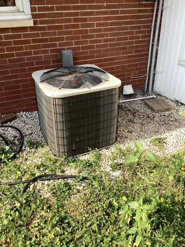 Responded to no cooling call where outdoor condenser unit was shutting down after approximately five minutes of operation and tripping the circuit breaker. Previous technician had replaced the capacitor, but issue persisted. Upon arrival, inspected the outdoor unit positioned against brick exterior and evaluated the Honeywell Home thermostat set to cool mode at 72°F while displaying 74°F ambient temperature. Documented equipment condition showing weathered condenser unit with darkened mesh grille and visible fan assembly. Performed diagnostic testing and warranty verification on system components to identify root cause of breaker tripping and premature shutdown cycle.