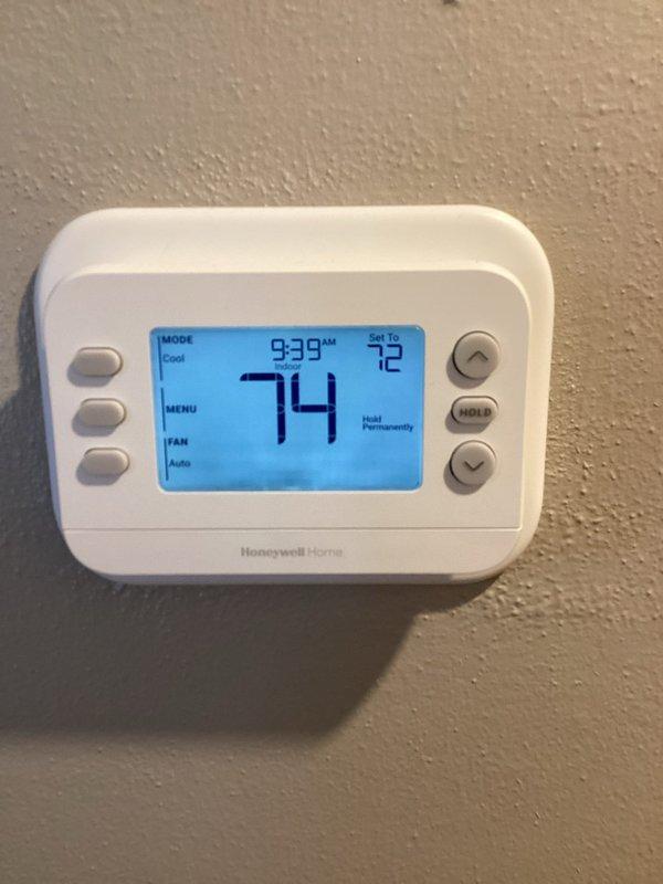 Responded to no cooling call where outdoor condenser unit was shutting down after approximately five minutes of operation and tripping the circuit breaker. Previous technician had replaced the capacitor, but issue persisted. Upon arrival, inspected the outdoor unit positioned against brick exterior and evaluated the Honeywell Home thermostat set to cool mode at 72°F while displaying 74°F ambient temperature. Documented equipment condition showing weathered condenser unit with darkened mesh grille and visible fan assembly. Performed diagnostic testing and warranty verification on system components to identify root cause of breaker tripping and premature shutdown cycle.