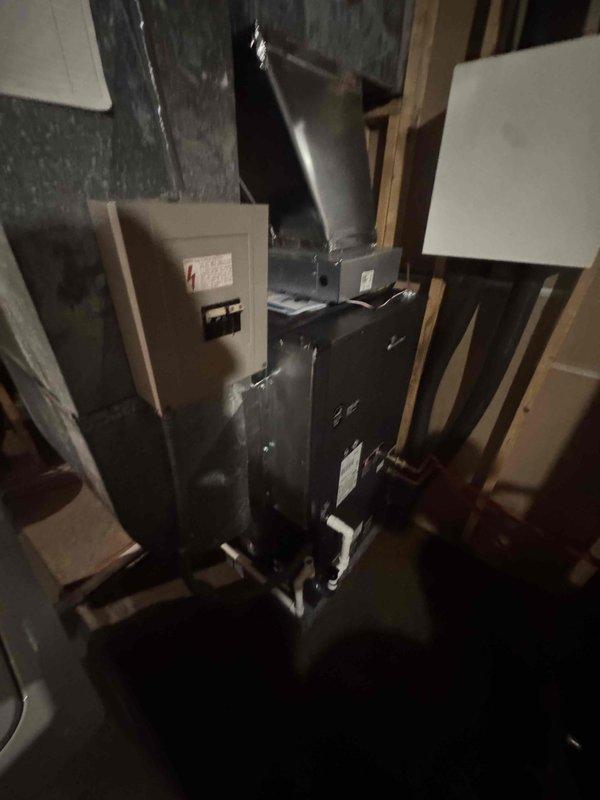 Completed geothermal HVAC system installation in residential utility space with vertical air handler unit, metal supply ductwork, and electrical disconnect panel. Installed and connected all ductwork transitions from unit to distribution system, secured electrical connections, and verified system pressures using calibrated gauge. System tested and operational upon completion.