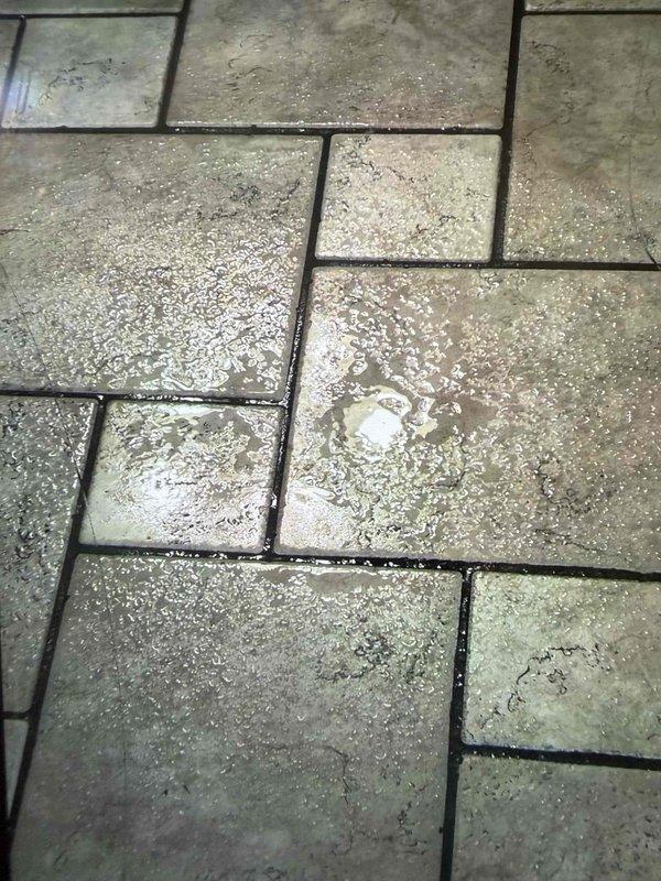 Responded to water leak emergency following previous unsuccessful leak detection attempt by another contractor. Upon investigation, located active water leak in attic space originating from plumbing system that became evident during shower usage. Inspected attic area, identified source of leak, and documented damage to floor surface below showing water staining, deterioration, and efflorescence on tile pavers. Completed necessary repairs to resolve leak issue and prevent further water damage to structure.