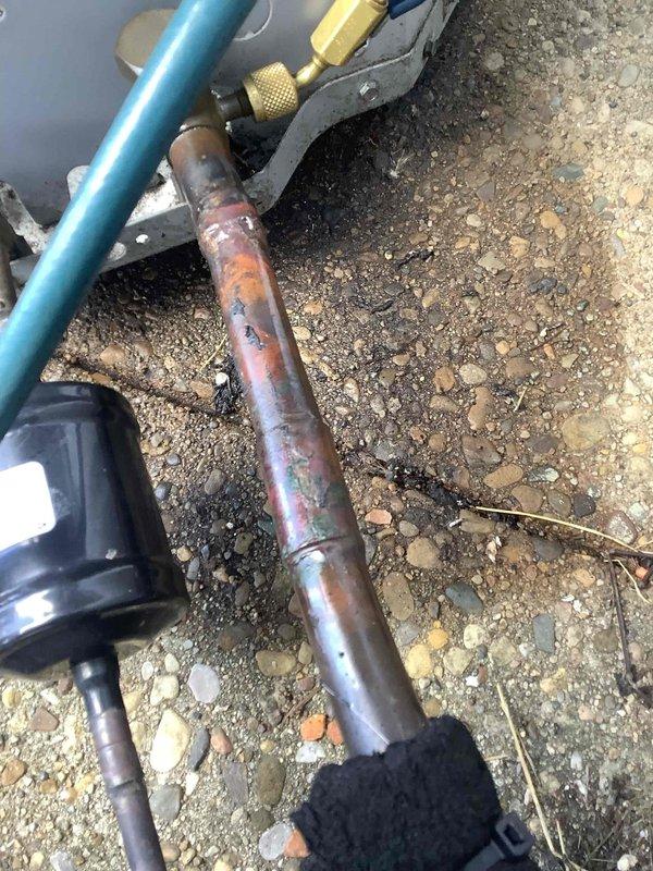 Responded to no-cooling call on outdoor air conditioning unit. Upon arrival, found unit completely inoperative with severely corroded copper refrigerant line showing extensive oxidation and deterioration from prolonged moisture exposure. Connected manifold gauges to diagnose system pressures and assess refrigerant circuit integrity. Identified failed refrigerant line as primary cause of system failure requiring replacement to restore operation.