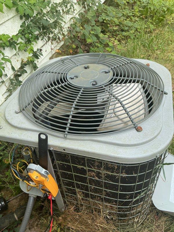 Completed comprehensive cooling season maintenance on single-zone residential HVAC system. Performed standard tune-up procedures on outdoor condenser unit, which showed signs of weathering and debris accumulation in lower mesh sections and around base. Removed dried grass, twigs, and plant debris from unit exterior and ventilation areas to ensure proper airflow. Inspected electrical connections and components, including visible wiring and exterior-mounted electrical meter. Examined indoor air handler and furnace assembly in basement utility area, verifying proper integration with ductwork and PVC condensate drainage system. All equipment operational following service; customer reported unusual whirring noise prior to appointment coinciding with area power outage, but no mechanical issues identified during inspection. System ready for cooling season operation.