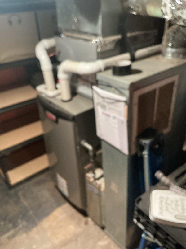 Completed comprehensive cooling season maintenance on single-zone residential HVAC system. Performed standard tune-up procedures on outdoor condenser unit, which showed signs of weathering and debris accumulation in lower mesh sections and around base. Removed dried grass, twigs, and plant debris from unit exterior and ventilation areas to ensure proper airflow. Inspected electrical connections and components, including visible wiring and exterior-mounted electrical meter. Examined indoor air handler and furnace assembly in basement utility area, verifying proper integration with ductwork and PVC condensate drainage system. All equipment operational following service; customer reported unusual whirring noise prior to appointment coinciding with area power outage, but no mechanical issues identified during inspection. System ready for cooling season operation.