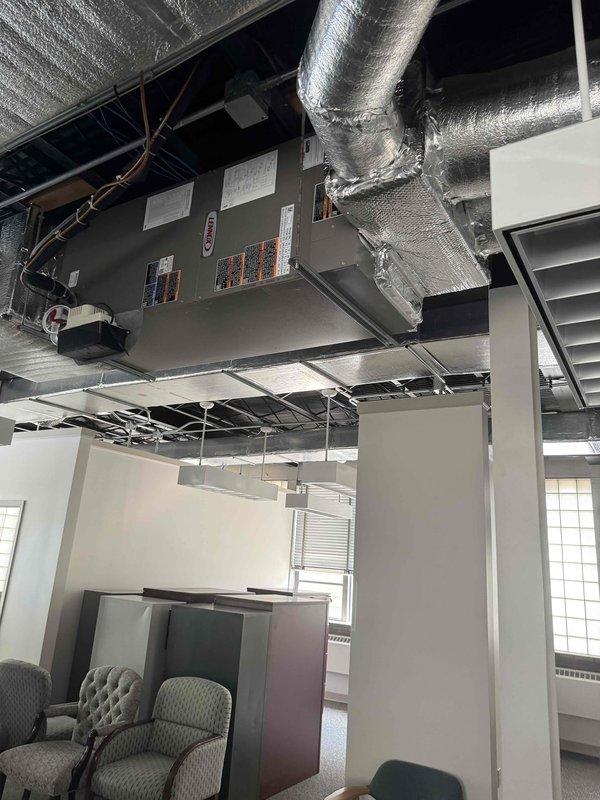 Completed full Lennox HVAC system installation including outdoor condensing unit and indoor evaporator coil at commercial office facility. Installed new cylindrical condenser on exterior concrete pad with proper refrigerant line sets and electrical connections routed along building exterior in protective conduit. Mounted air handling unit with evaporator coil in exposed ceiling space, integrated with existing ductwork using reflective insulation wrapping for thermal efficiency. System tested, charged to manufacturer specifications, and verified operational.