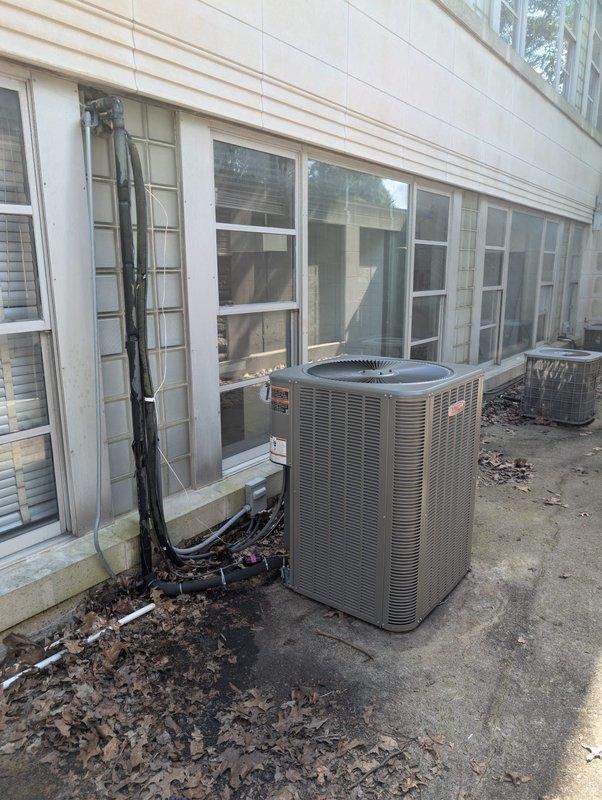 Completed full Lennox HVAC system installation including outdoor condensing unit and indoor evaporator coil at commercial office facility. Installed new cylindrical condenser on exterior concrete pad with proper refrigerant line sets and electrical connections routed along building exterior in protective conduit. Mounted air handling unit with evaporator coil in exposed ceiling space, integrated with existing ductwork using reflective insulation wrapping for thermal efficiency. System tested, charged to manufacturer specifications, and verified operational.