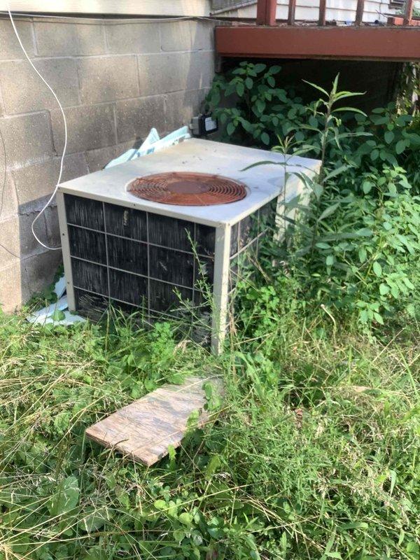 Responded to no-cooling complaint on residential split system air conditioning unit. Upon arrival, found outdoor condenser unit surrounded by overgrown vegetation and debris, restricting airflow to unit. Performed diagnostic testing of system components using digital multimeter and HVAC testing equipment. Cleared excessive weeds and plant growth from around condenser base and sides to restore proper airflow clearance. Inspected condenser coil, fan operation, and electrical connections. System restored to proper cooling operation after clearing obstructions and completing diagnostics.