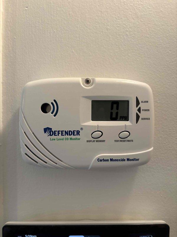 Completed full installation of Lennox heat pump and gas furnace system at residential property. Outdoor condenser unit properly positioned on concrete pad with adequate clearance for airflow and service access. Interior installation included low-level carbon monoxide detector with digital display, alarm functionality, and test/reset capabilities to ensure safe operation of gas-fired equipment.