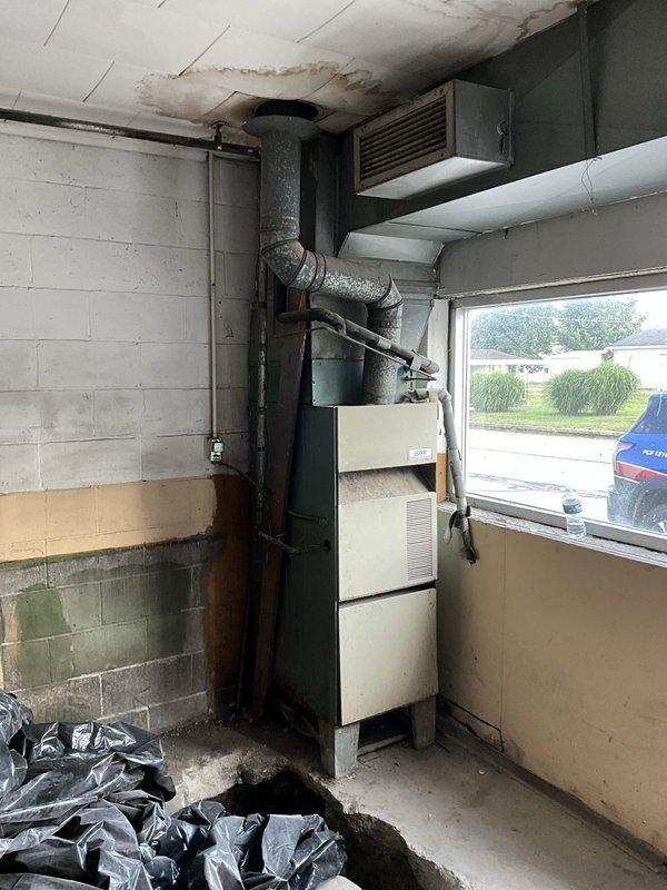 Conducted comprehensive site evaluation for commercial HVAC system replacement in utility room with existing aging furnace unit showing signs of wear and water damage to surrounding infrastructure. Documented current equipment configuration including ductwork layout, electrical panel connections, and spatial constraints for new installation planning. Provided detailed photographic documentation and prepared full system replacement estimate for customer review.