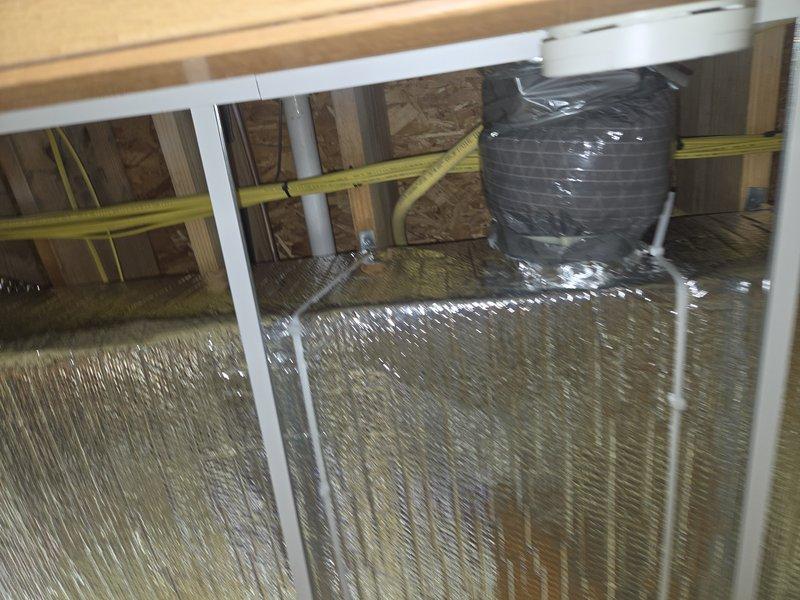 Wrapped exposed trunk line ductwork in reflective foil insulation within the attic space and reconnected the return air duct to the HVAC system. All ductwork connections were properly secured and the system was restored to full operational status.