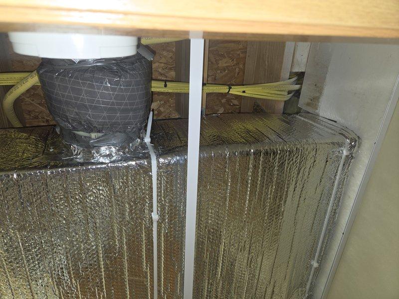 Wrapped exposed trunk line ductwork in reflective foil insulation within the attic space and reconnected the return air duct to the HVAC system. All ductwork connections were properly secured and the system was restored to full operational status.