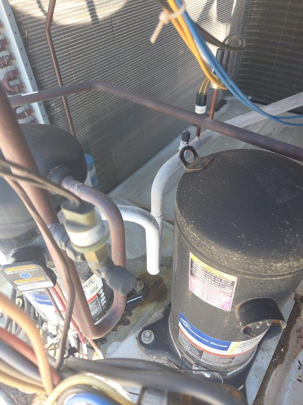 Accessed rooftop unit via interior second-floor hatch and performed A/C service inspection. Verified Honeywell digital thermostat operation showing 65° with system in cooling mode and auto fan setting. Inspected rooftop compressor unit, refrigerant lines, condenser coil, and associated components; noted normal operational wear consistent with equipment age and outdoor exposure.