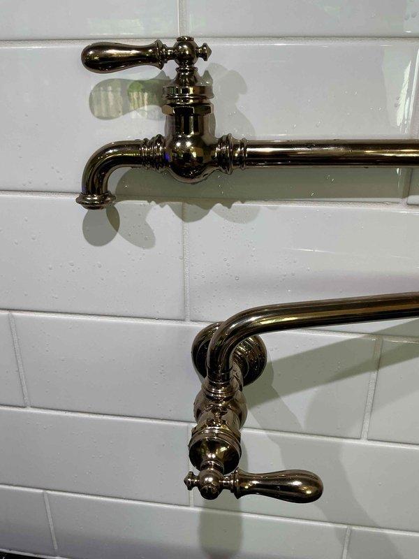 Responded to emergency call for leaking pot filler fixture in commercial facility. Upon arrival, identified active leak at first joint connection from wall valve where spray was occurring during operation. Inspected brass pot filler assembly mounted on subway tile wall, documented condition with photos, and assessed valve connection point requiring repair to restore proper function and prevent water damage.