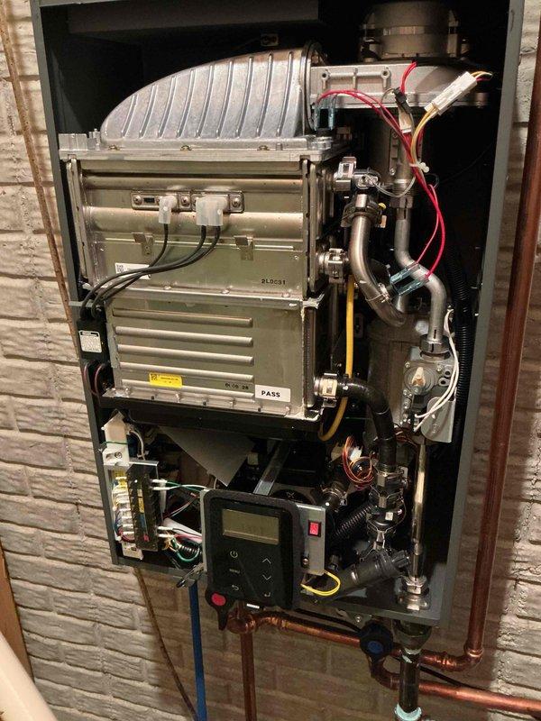 Responded to service call for tankless water heater experiencing intermittent cycling issues within first year of installation. Upon arrival, performed diagnostic inspection of wall-mounted tankless unit and associated components. Evaluated control panel display readings, examined electrical connections including red and yellow wiring, and inspected all plumbing connections including copper supply lines and gas line. Checked system sensors, flow rates, and thermostat settings to identify cause of random on/off cycling behavior. Verified proper venting, assessed heat exchanger condition, and tested all valves and safety mechanisms. Documented system configuration with photographs showing complete installation including digital control interface, piping assembly, and mounting within recessed wall cavity. Addressed cycling issue and verified unit returned to normal operation without false starts or unexpected shutdowns.